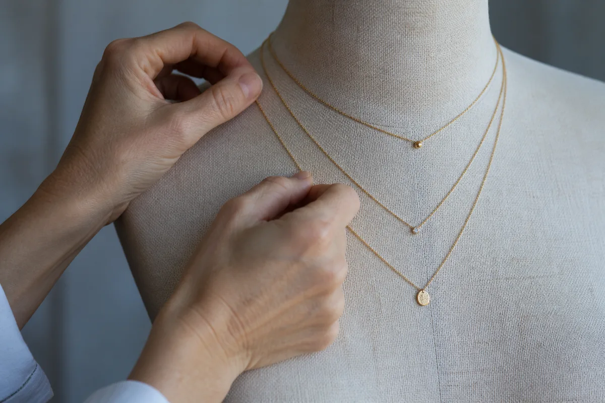 Colliers fins de longueurs différentes superposés sur un buste de couture en lin