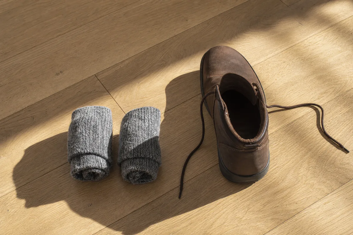 Chaussettes en laine épaisse posées près d&rsquo;une chaussure en cuir sur un parquet clair