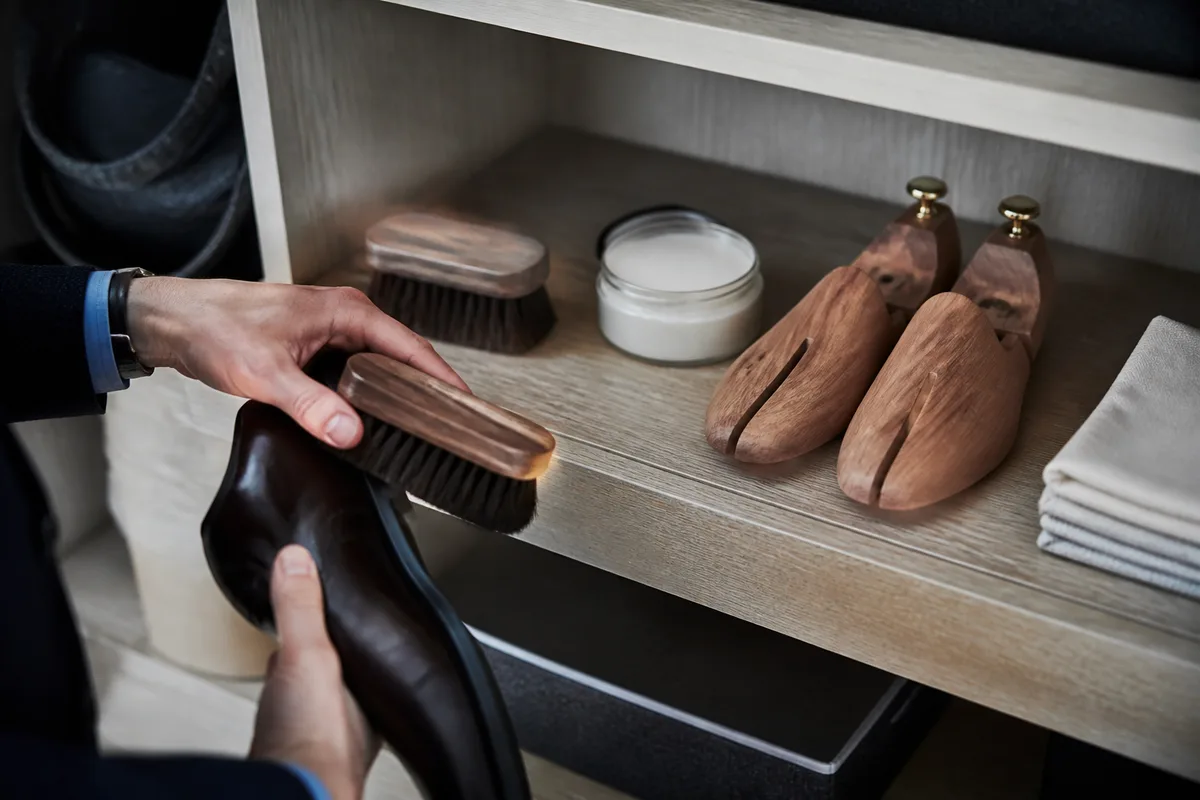 Brosses, crème et embauchoirs en cèdre réunis sur une étagère en bois