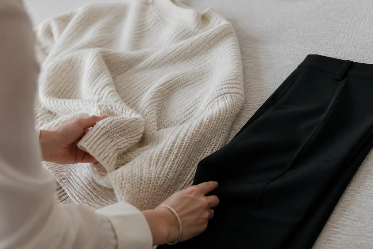 Pull ample posé à côté d’un pantalon ajusté, contraste des volumes sur fond neutre